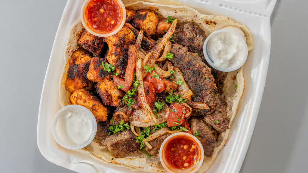 A container of meats and hummus and vegetables.