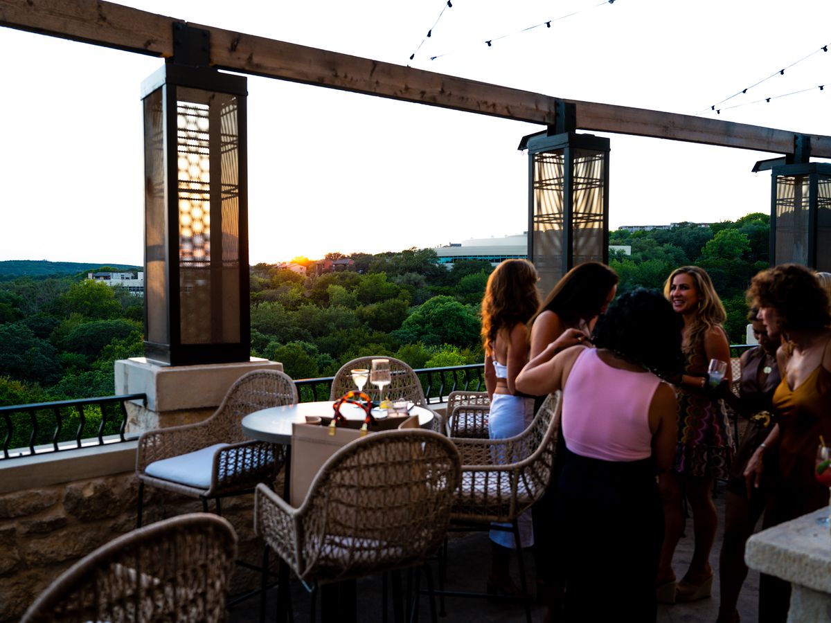 A restaurant patio with a group of women and trees in the distance. 