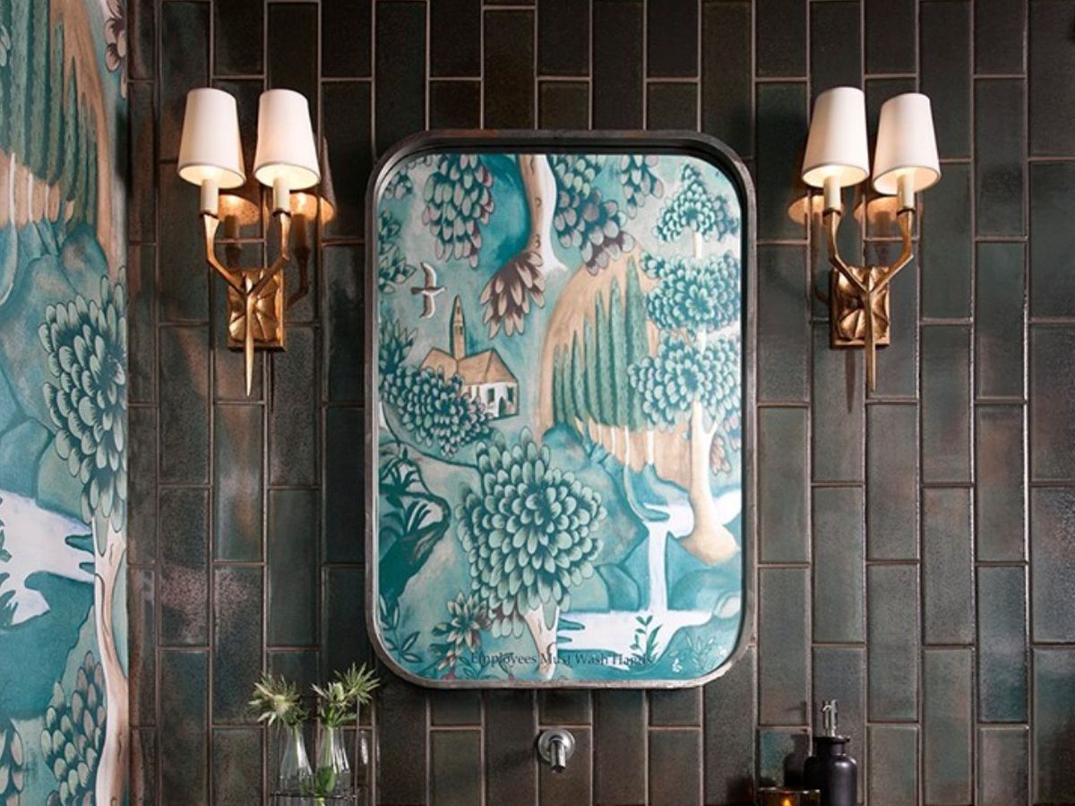 A bathroom with a mirror reflecting a blue landscape wallpaper.