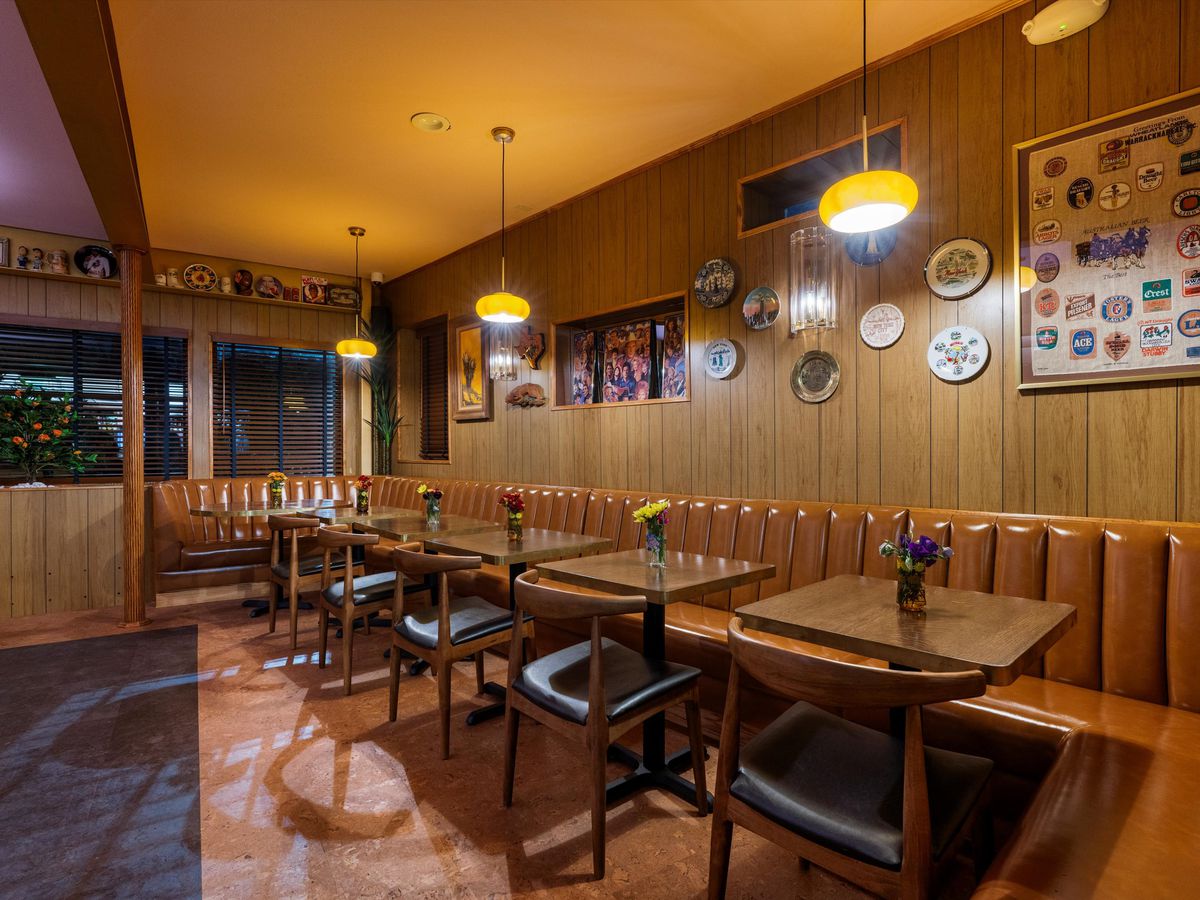 A restaurant dining room with leather banquettes and tables.