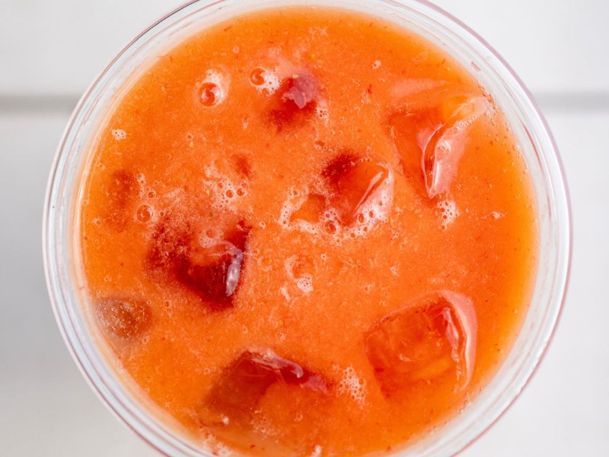 An orange drink with ice cubes seen from above.
