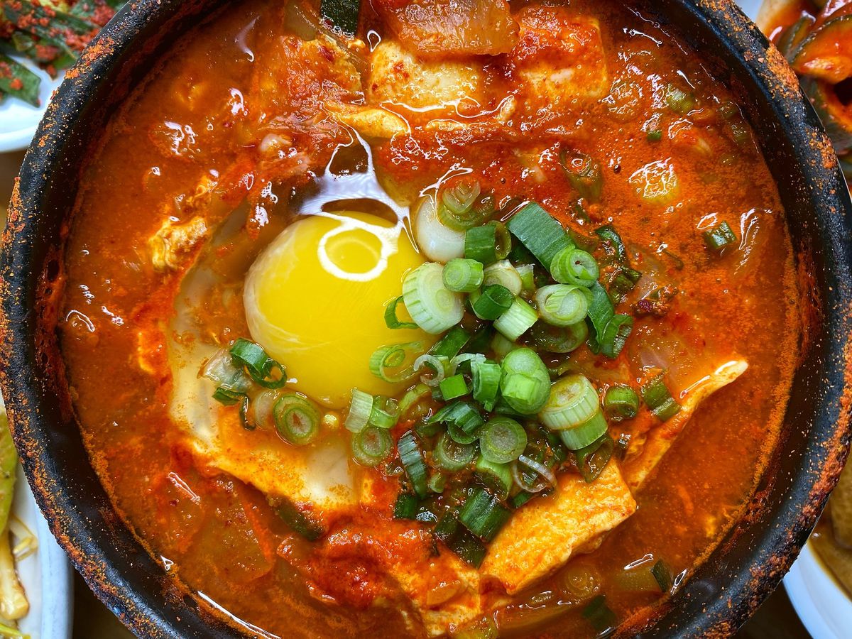 A pot of red stew with an egg on top of it.