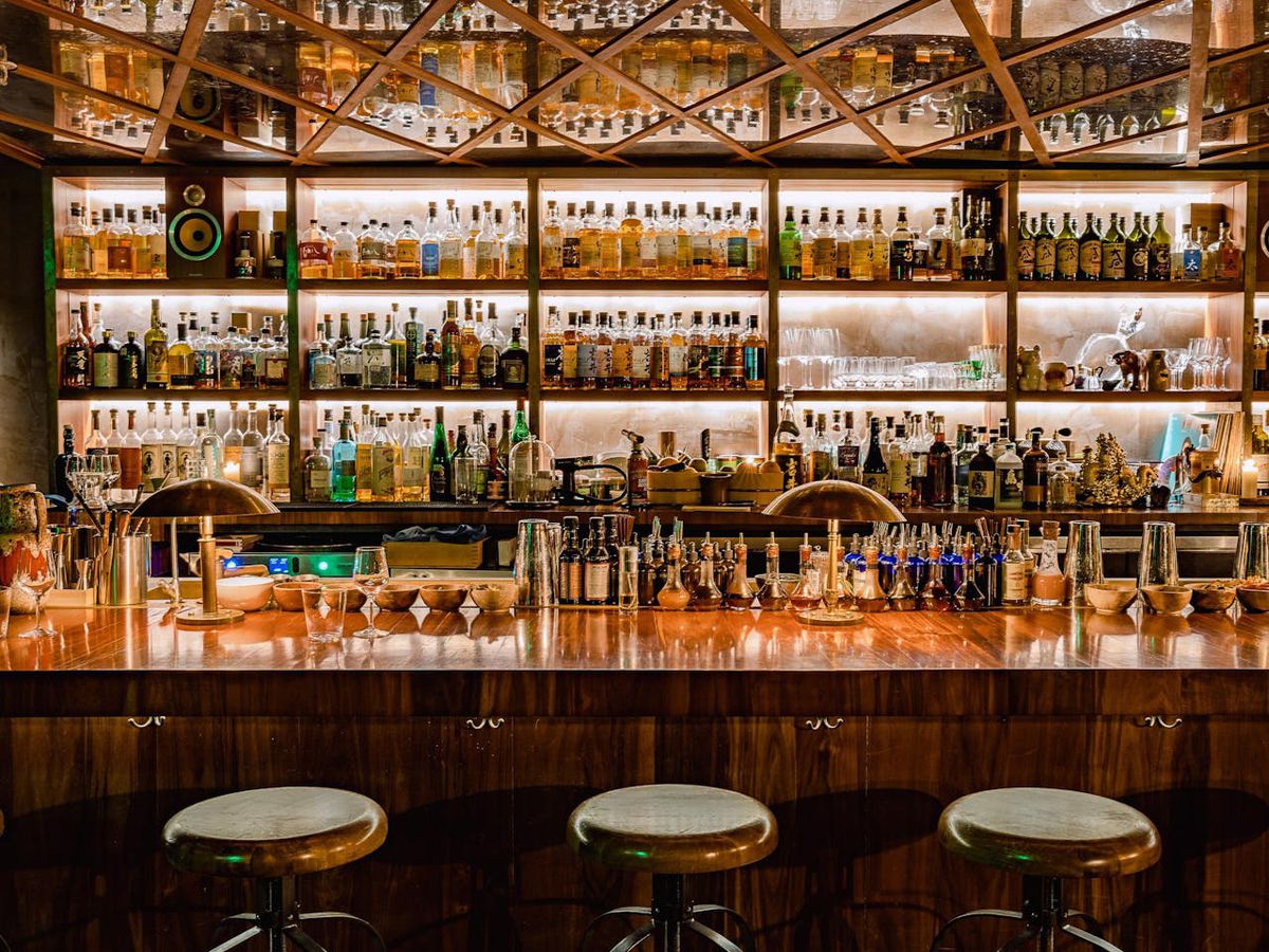 A cocktail bar with shelves of liquor bottles.