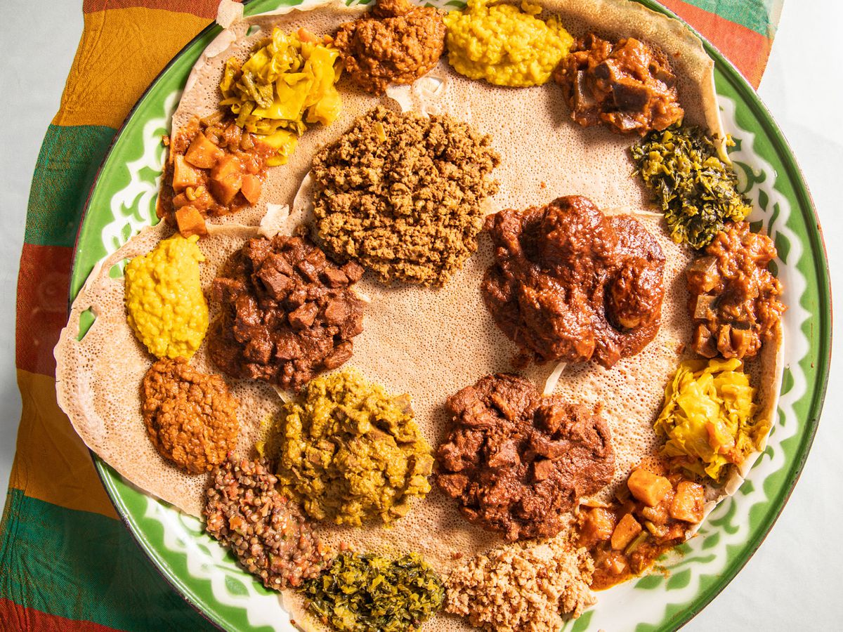A round bread with dollops of curries and meats on top of it. 