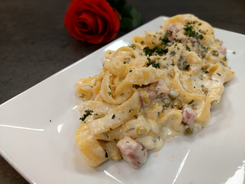 A plate of fettuccini with ham chunks.