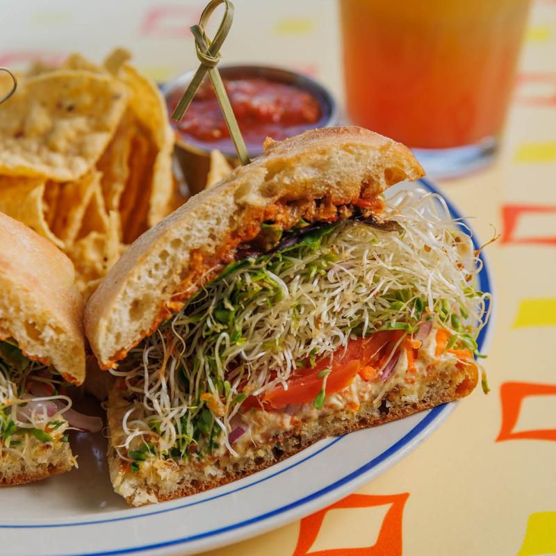 A sandwich is loaded with sprouts and tomatoes.
