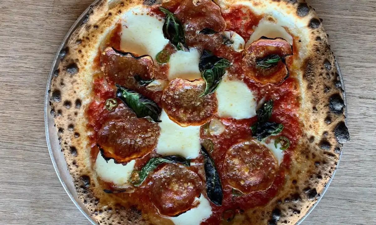 A calabrese Neapolitan pizza sits on a silver tray on a table.