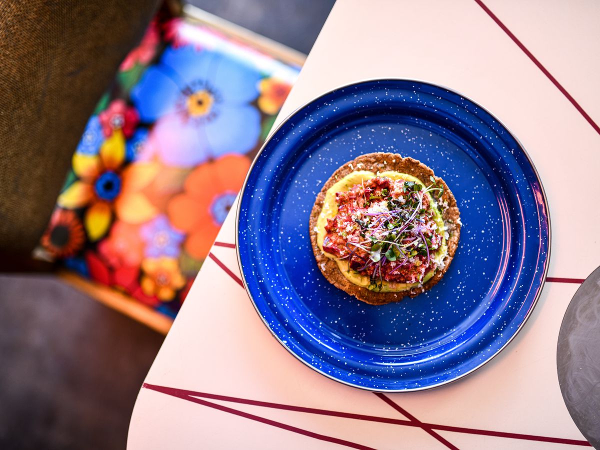 A blue plate with a circular tostada with pink beets on it.