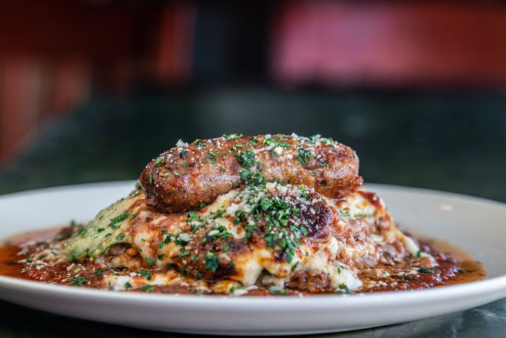 A plate holds a mound of polenta with an Italian sausage on top.