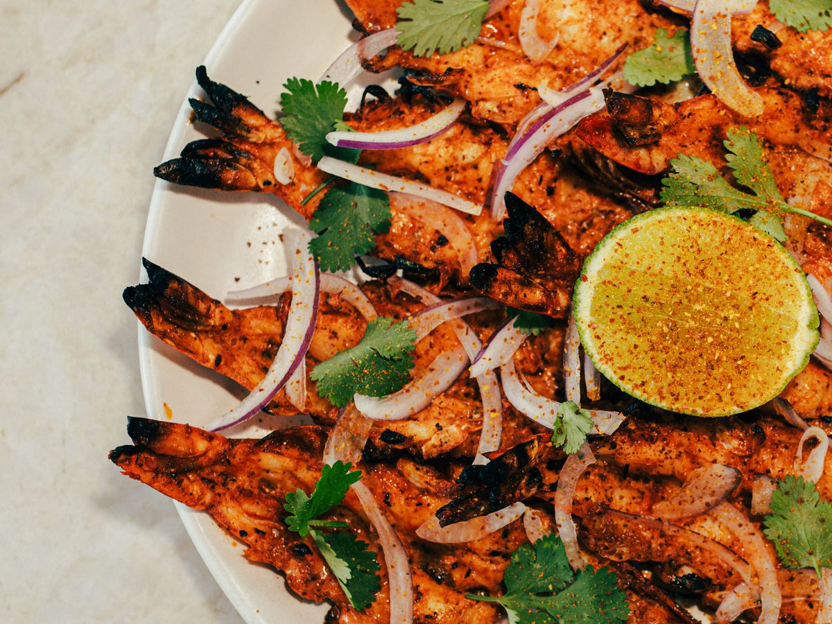 Halved-grilled shrimp with onions on it and a halved lime.