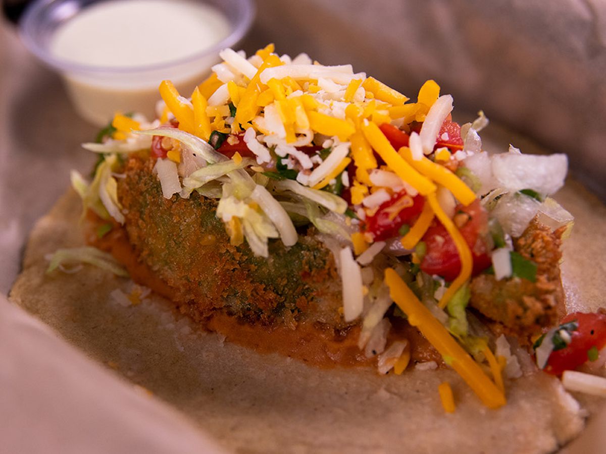 A taco with a fried avocado and toppings.
