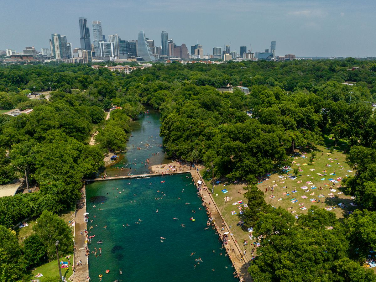 A swimming pool seen from above with a city skyline in the background.