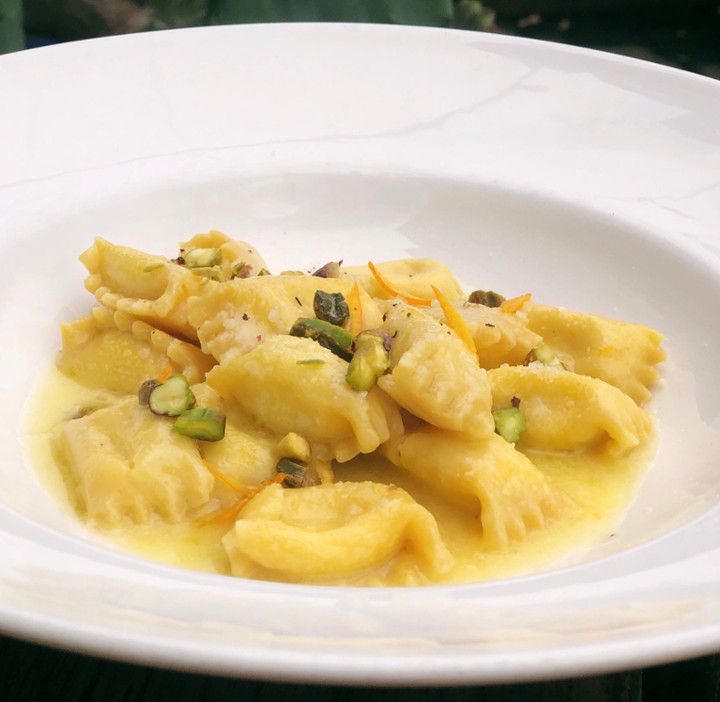A dish holds agnolotti with goat cheese, Parmigiano reggiano, and pistacchio.