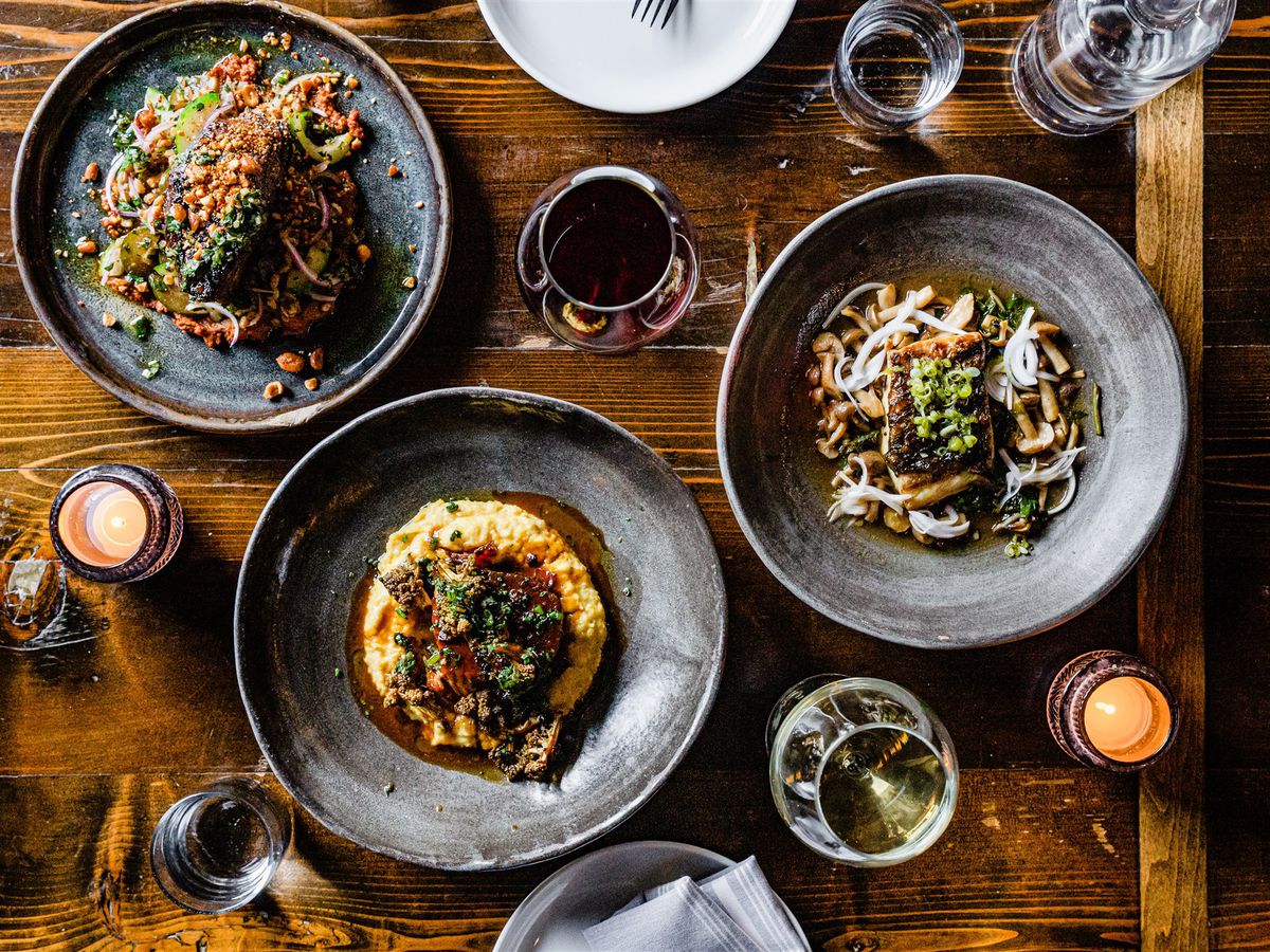 A table holds three dishes (L to R) a salad, polenta with au jus, and pasta.