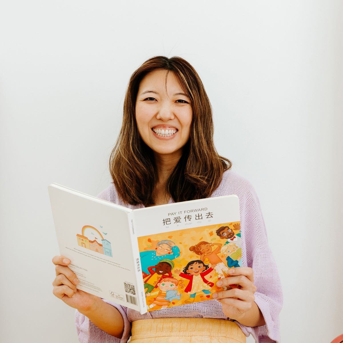 Irene Kang smiles for a photo holding one of her books.