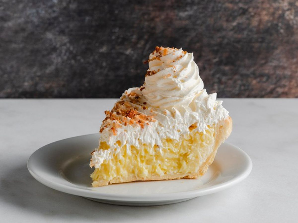 A slice of custard pie with whipped cream on top of it. 
