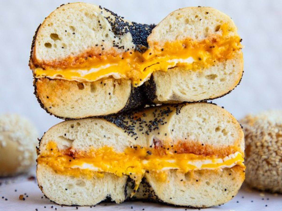 A halved bagel sandwich with cheese and eggs.