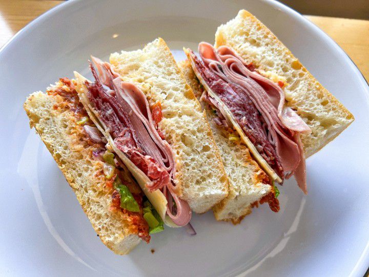 A sandwich with meats and cheese and sauces. 