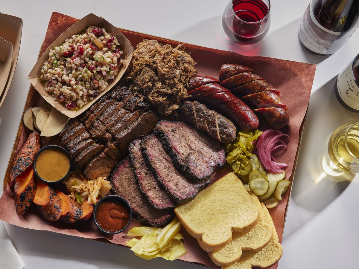 A tray with sliced meats, sides, and breads.