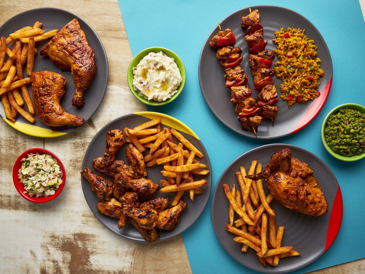 A table of chicken and other foods in plates.