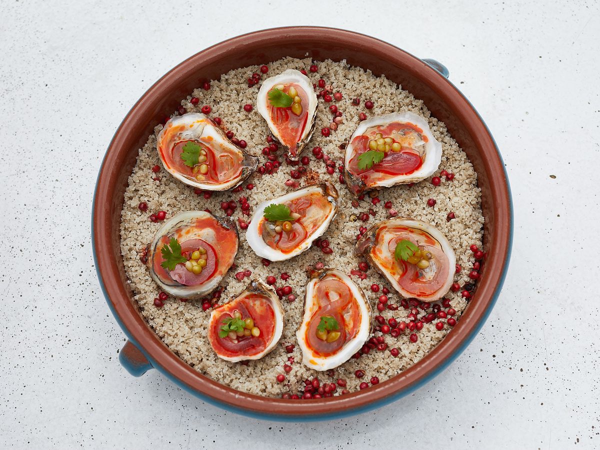 A round tray of dressed ousters in a red sauce.
