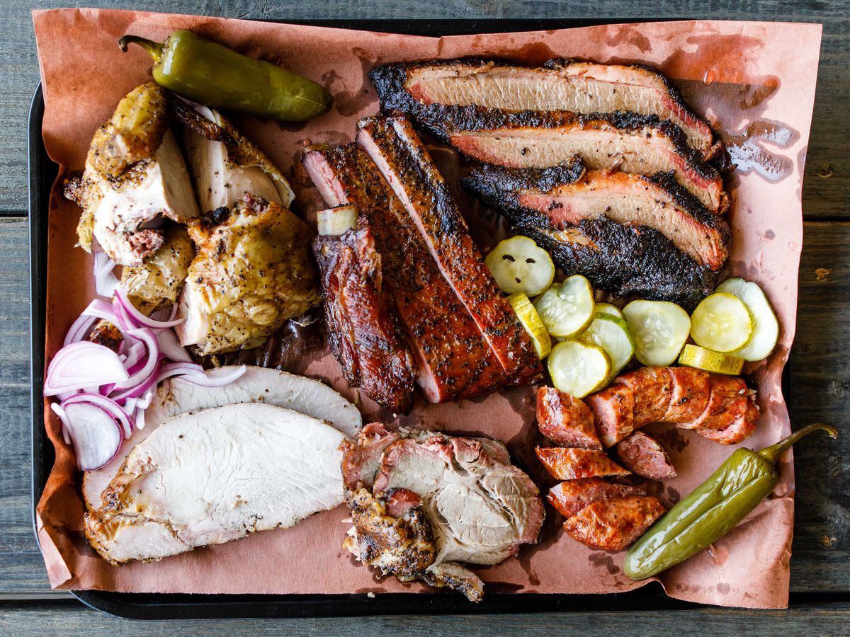 a barbecue tray filled with smoked meats, pickles, onions, and jalapenos.