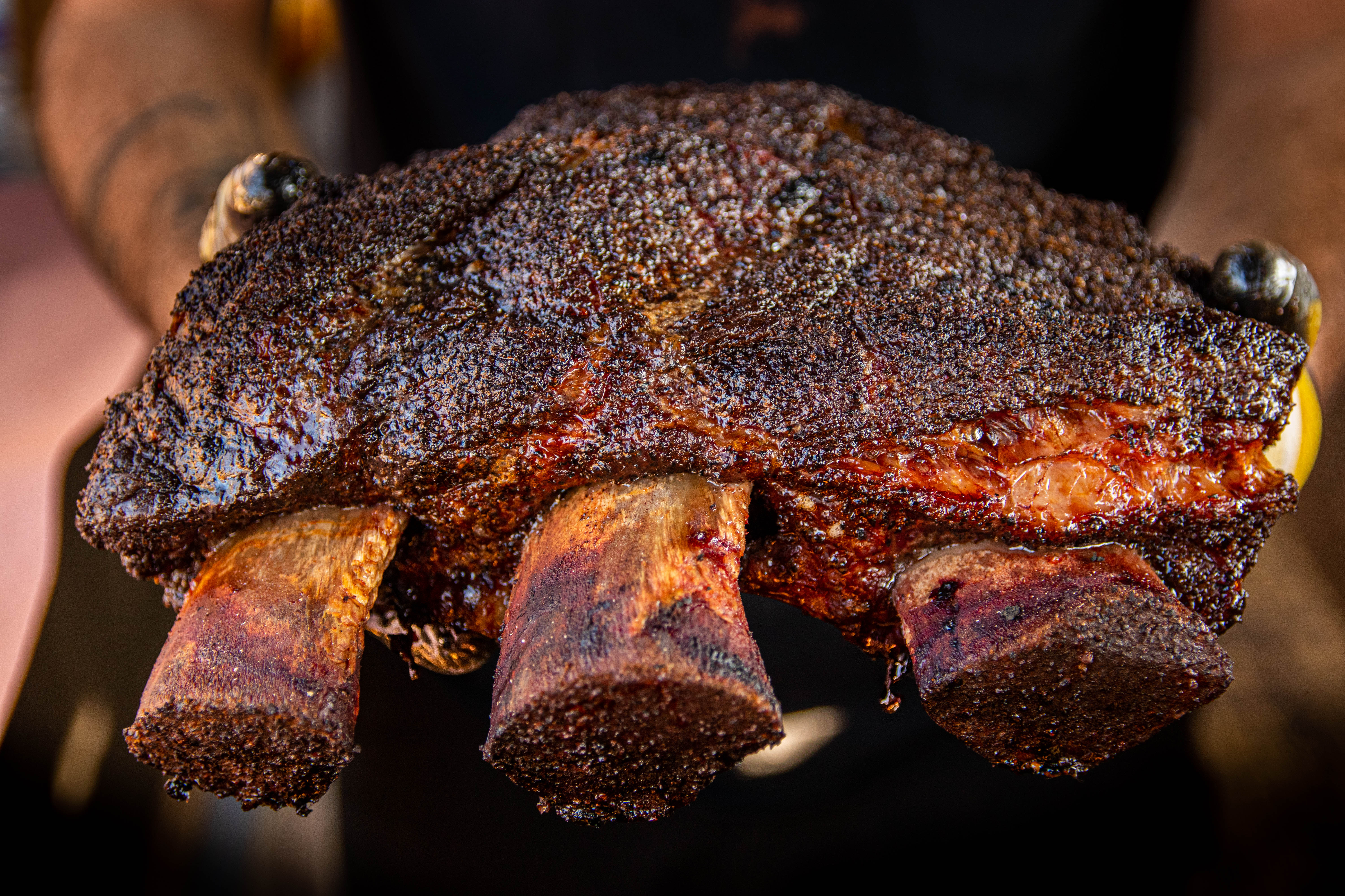 Someone holding up a giant rack of barbecued ribs.