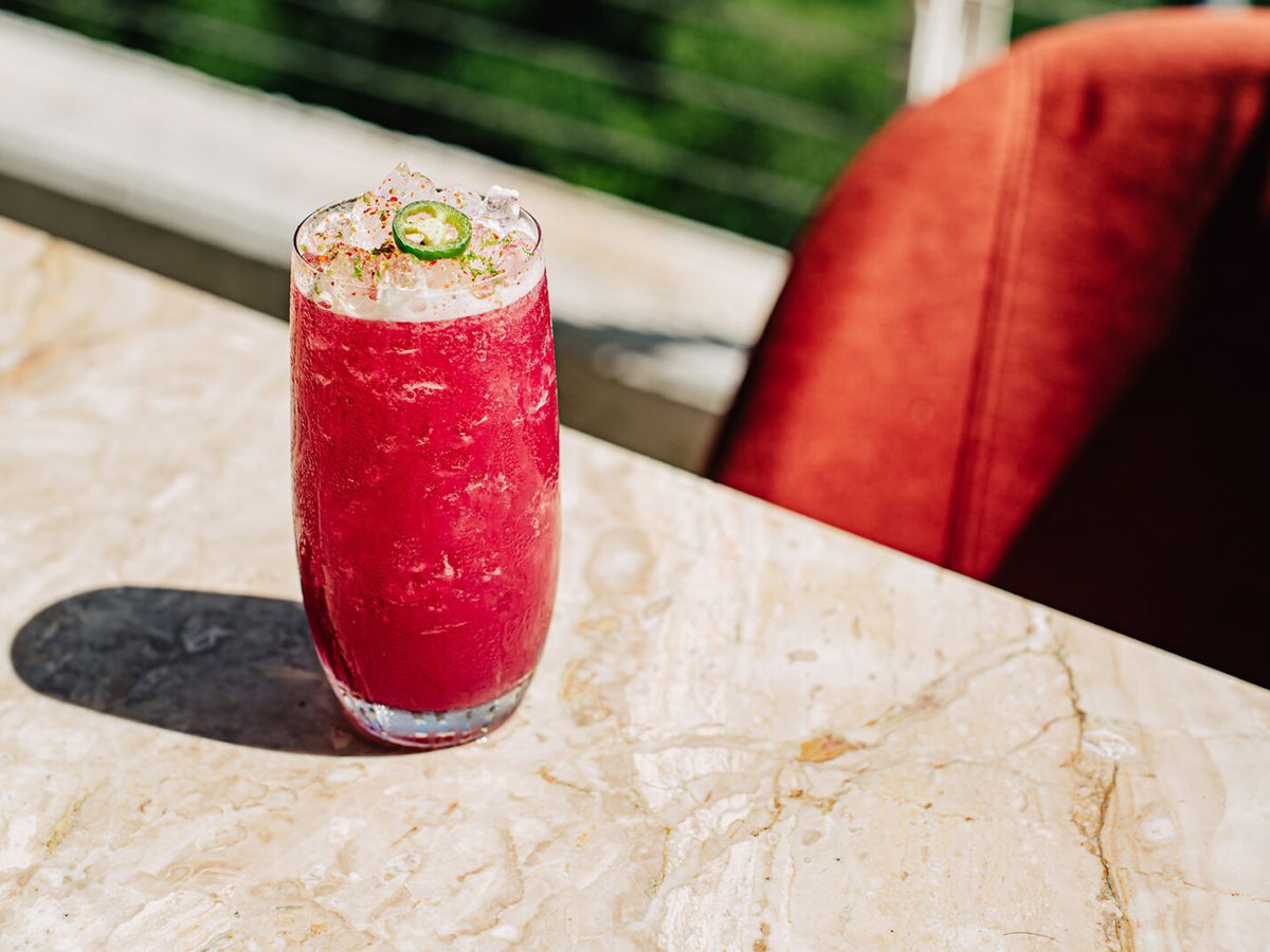A pink drink with crushed ice sits on a marble tabletop.