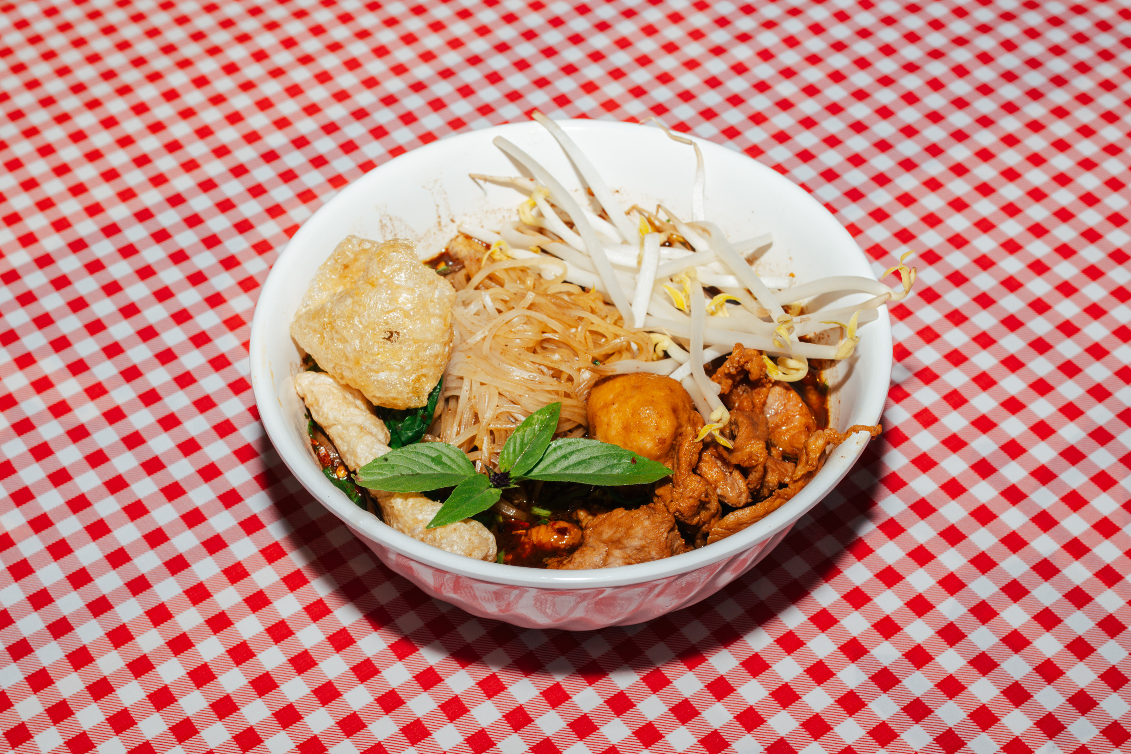 A bowl of noodles and vegetables and meats.