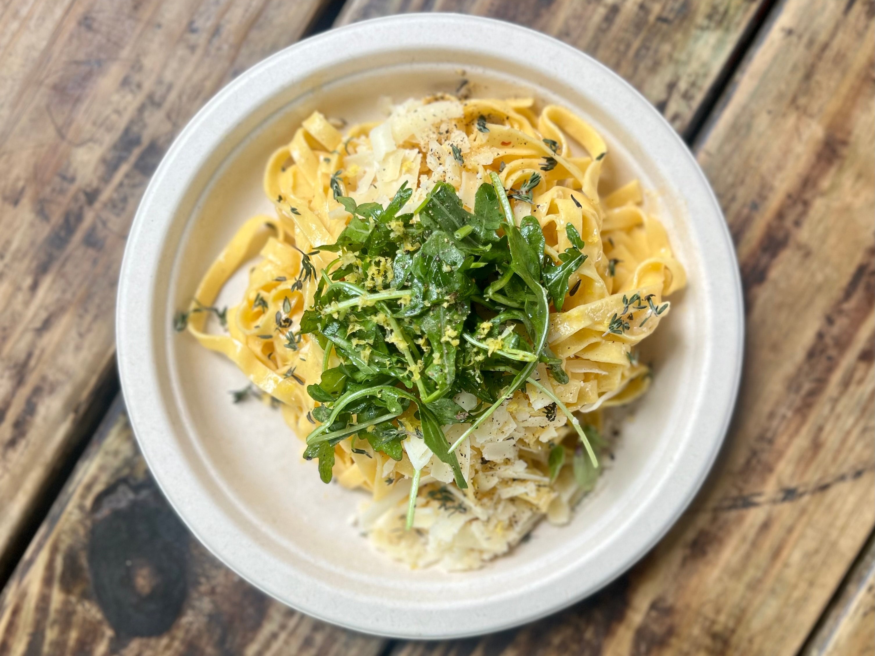 A plate holds fresh pasta with lemon and thyme.