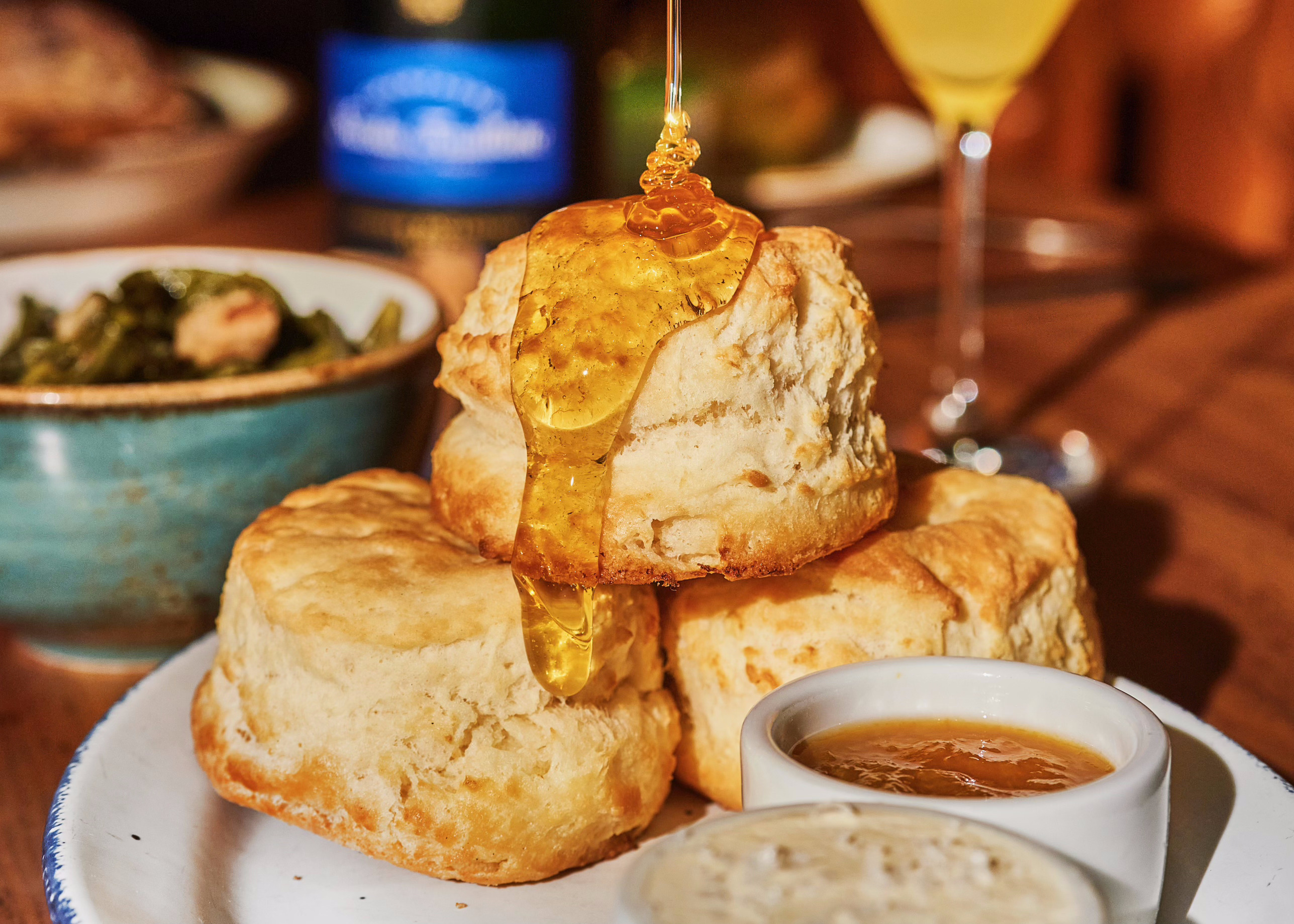Someone pouring honey on a pile of biscuits on a plate.