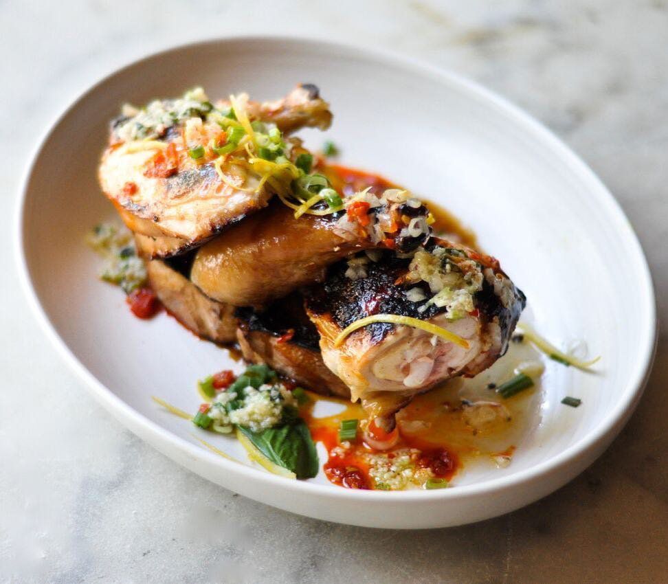 A plate with roast chicken legs covered in garlic and olive oil.