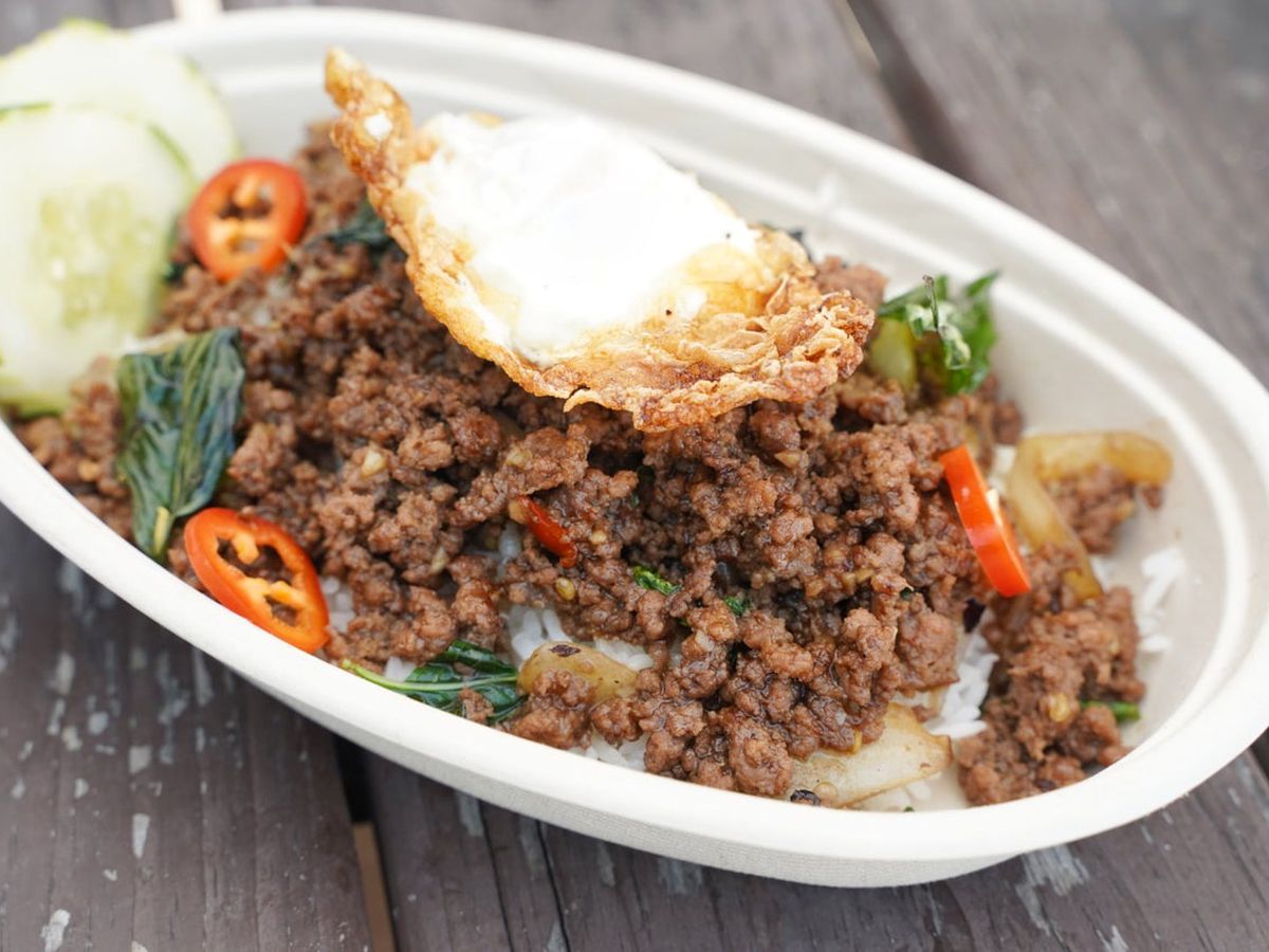 An oval plate of ground meat, fried egg, and sliced red peppers.
