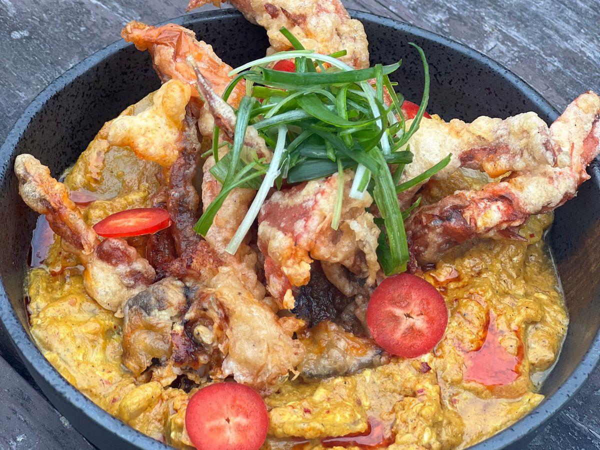 A bowl of curry and fried crab.
