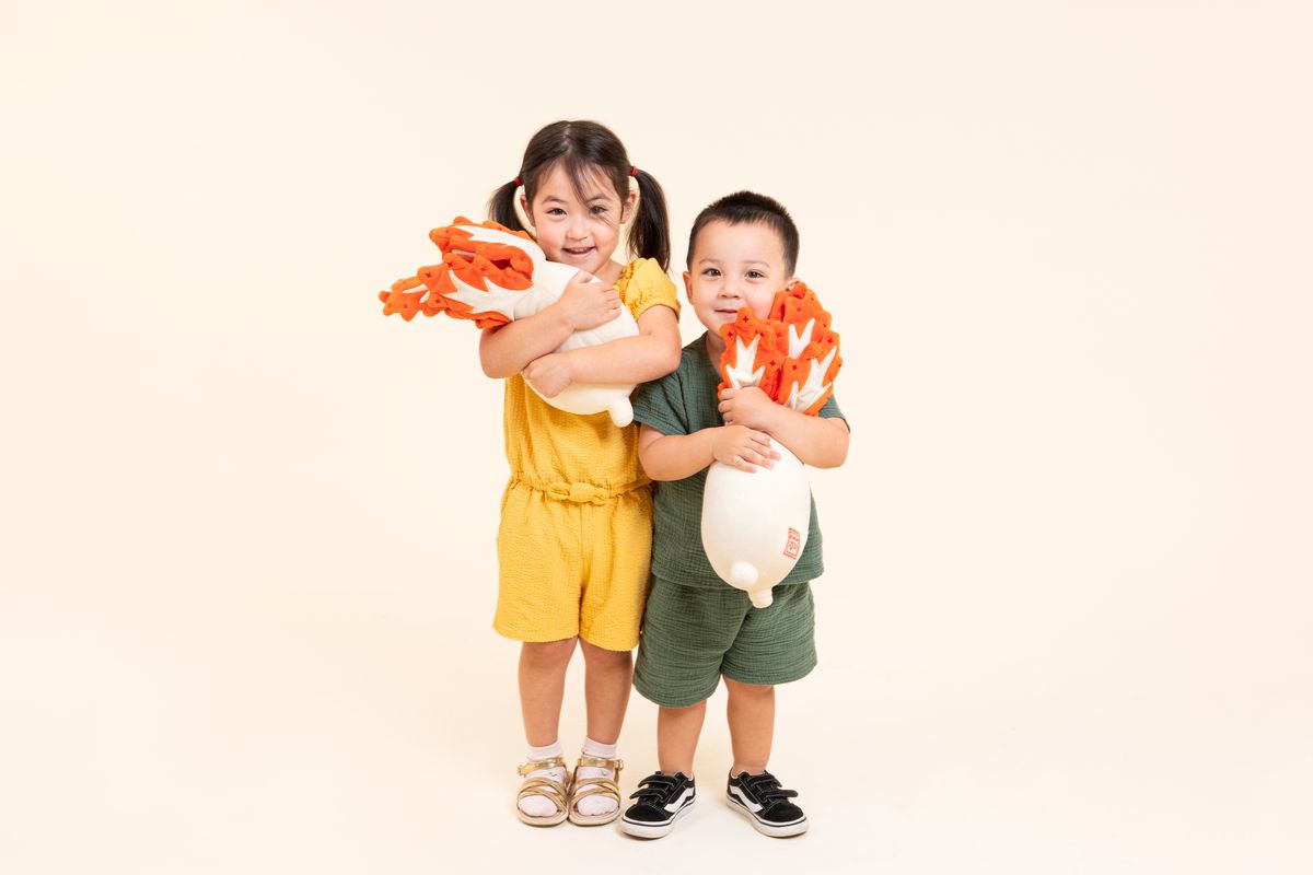 Children hug kimchi plushies.