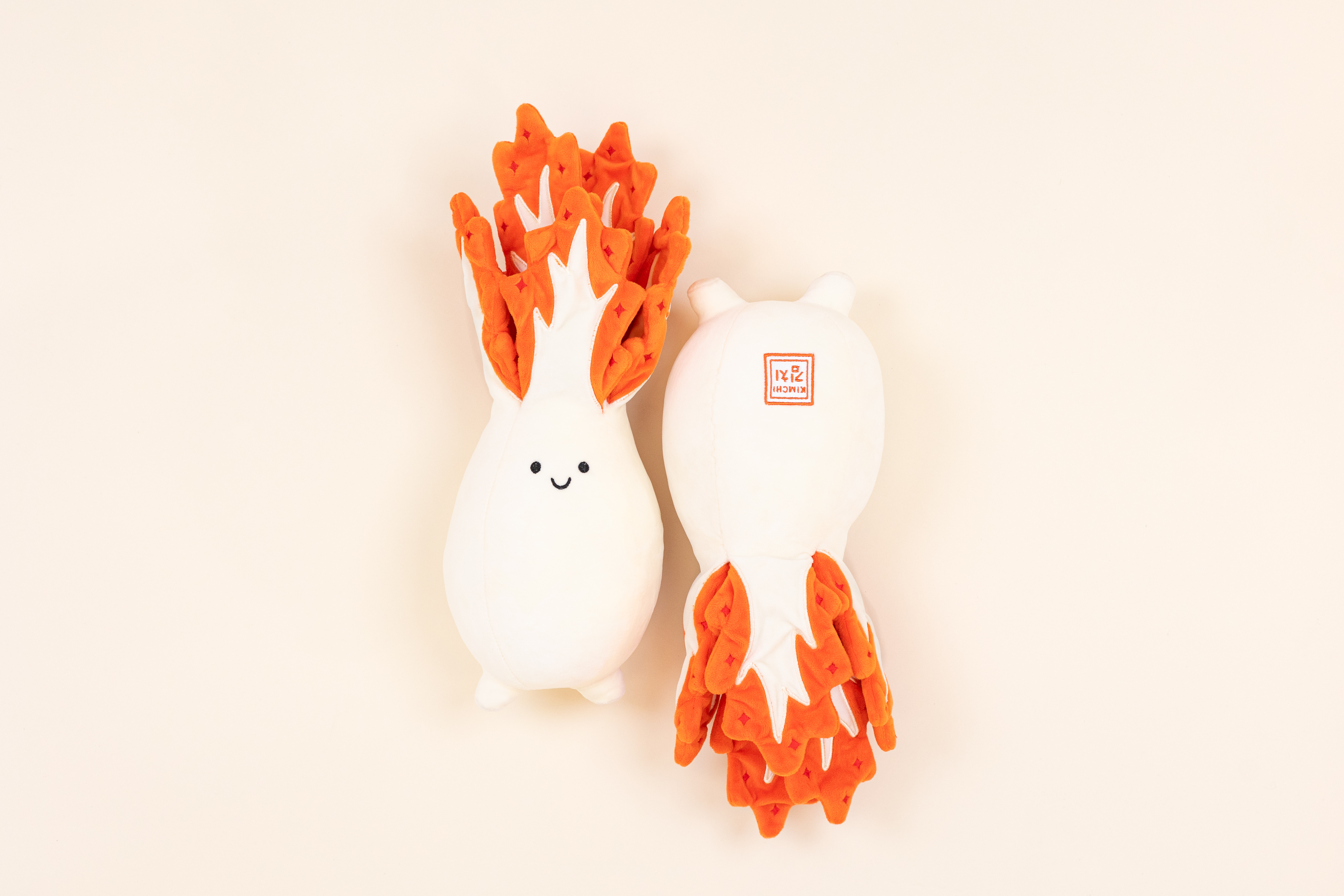 Two kimchi plushies lay side by side.
