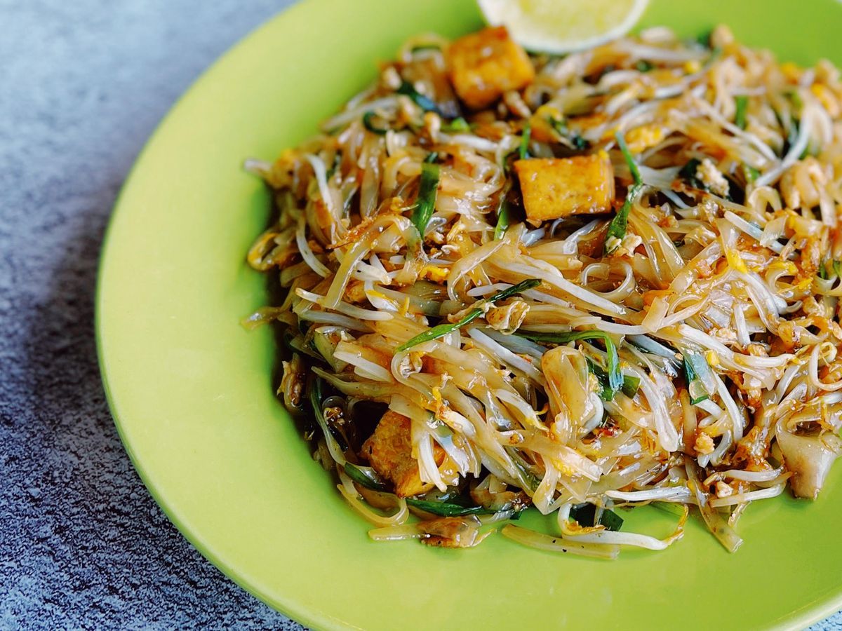 A green plate holds tofu pad Thai.