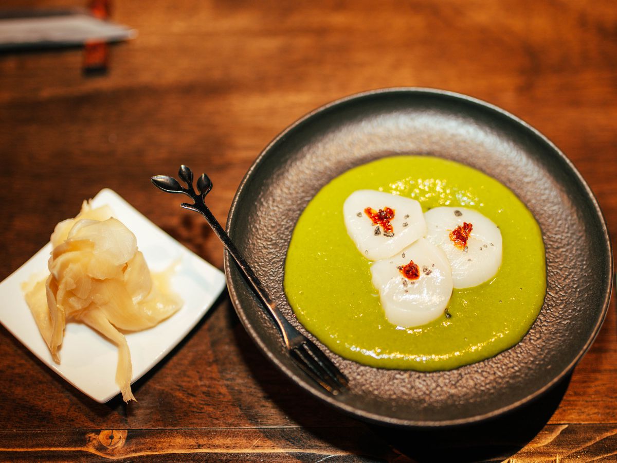 A plate of scallops on a green sauce.