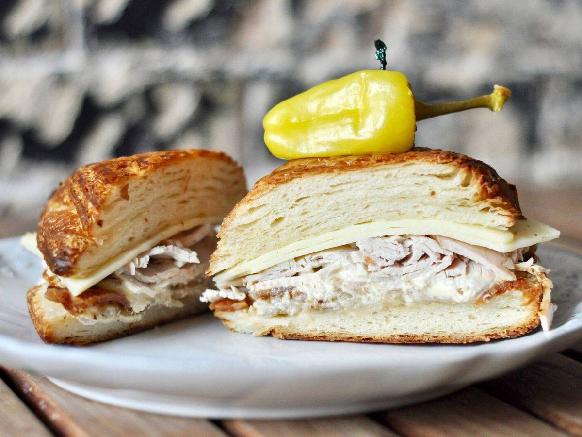 A halved croissant sandwich with layers of turkey.